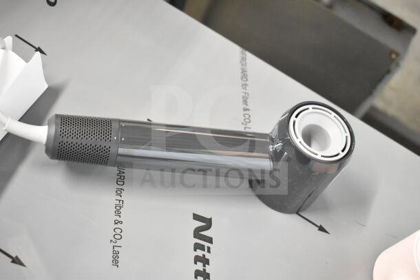 Hair dryer with cut power cord on display, part of a lot including hair dryers and brushes. Ideal for parts or repair.