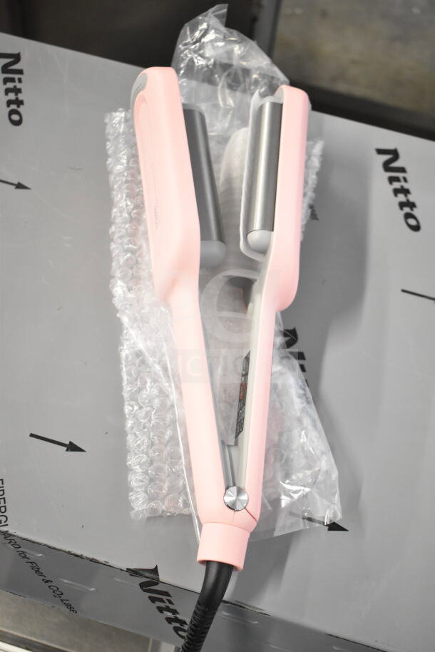 Pink hair straightener laid on bubble wrap, with a cut power cord. Part of a 6-item lot including hair dryers and brushes.