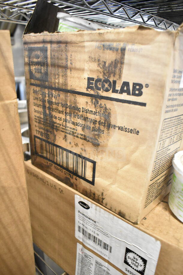 Cardboard boxes of Ecolab 6100122 Foam Hand Soap and Diversey Prominence Heavy Duty Floor Cleaner on a shelf, visible wear.