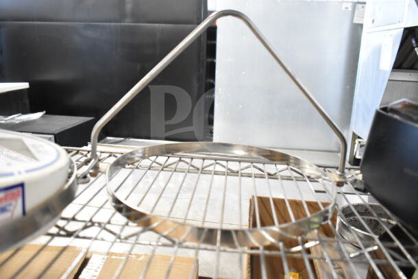Detecto SCS30 hanging produce scale with two metal pieces, shown on a shelf, indicating industrial use and versatility.