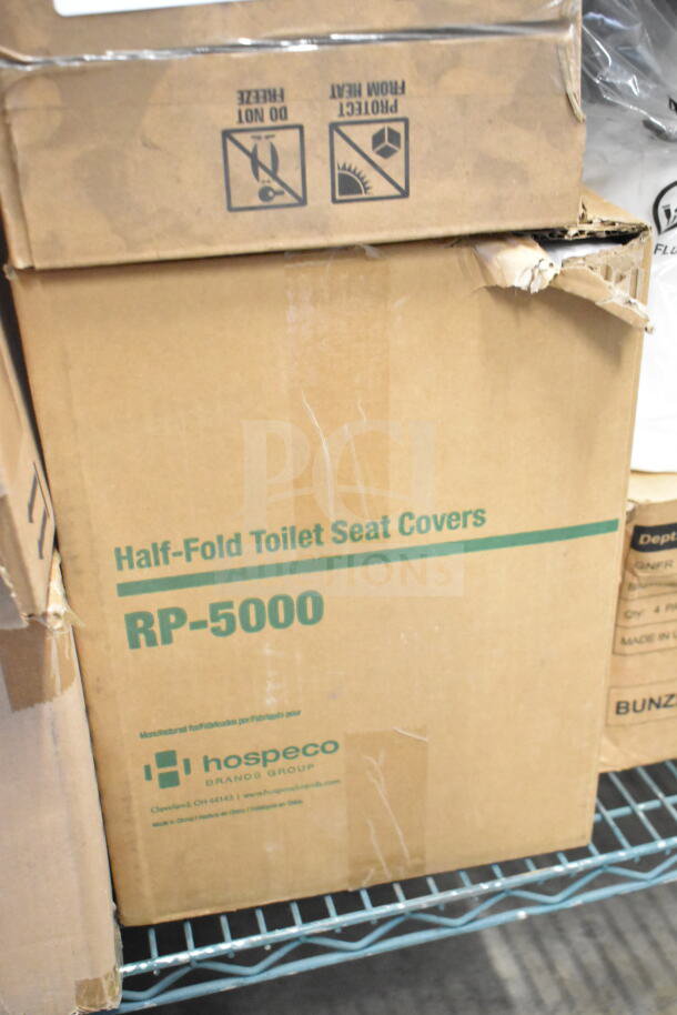 Cardboard box of Hospeco RP-5000 Half-Fold Toilet Seat Covers, brand new, with visible dent on side.