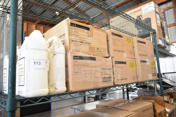 Boxes of Biopure BZK Wipes and various items on a metal shelf, labeled as new scratch and dent auction items.