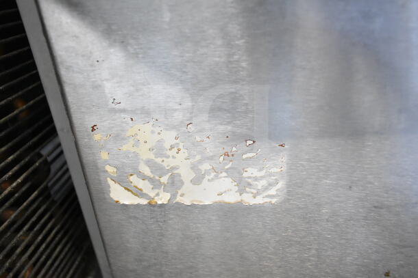 Commercial countertop flat top griddle with cheese melter; visible surface wear with peeling paint on the metal exterior.
