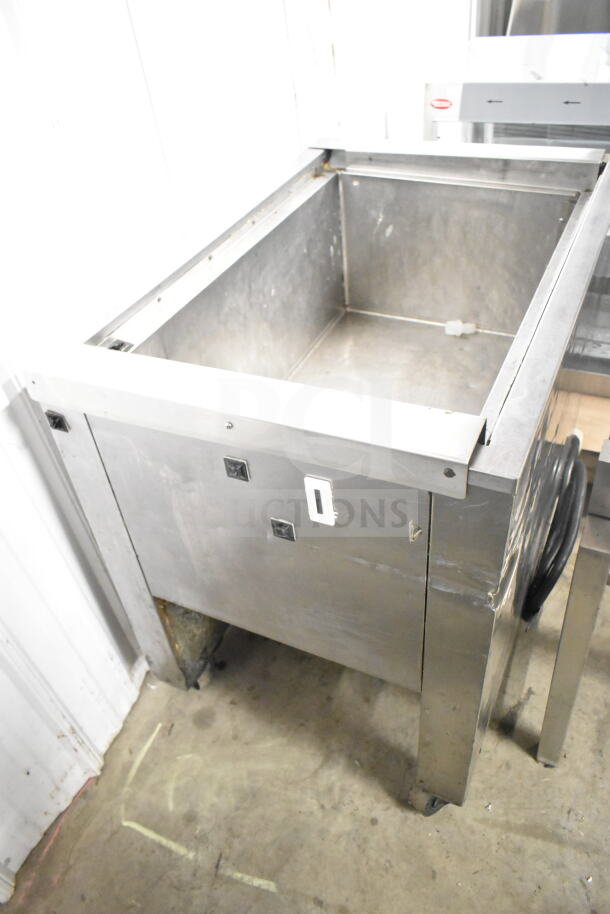 Commercial stainless steel chest freezer on casters, showing wear. Ideal for restaurant use.