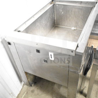 Commercial stainless steel chest freezer on casters, showing wear. Ideal for restaurant use.