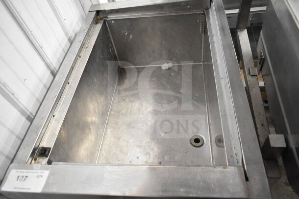 Commercial chest freezer on casters, open stainless steel interior, fair condition, some visible wear.