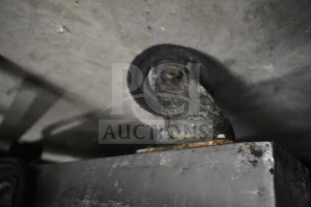 A close-up of a commercial caster attached to a chest freezer, showing signs of wear and rust.