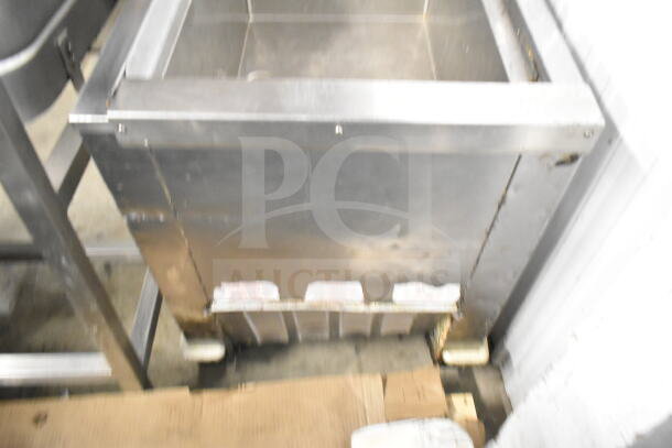 Commercial chest freezer on casters, used condition, stainless steel exterior, slight wear visible, ideal for kitchens.