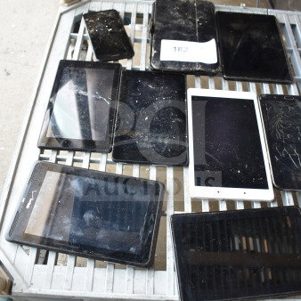 Various tablets on metal rack, mostly with cracked or dirty screens, indicating used condition. One visible label marked "182".