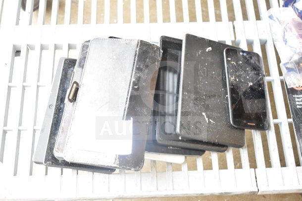 Nine assorted tablets and devices, various conditions, visible wear, includes Kindle and other models. Auction lot.