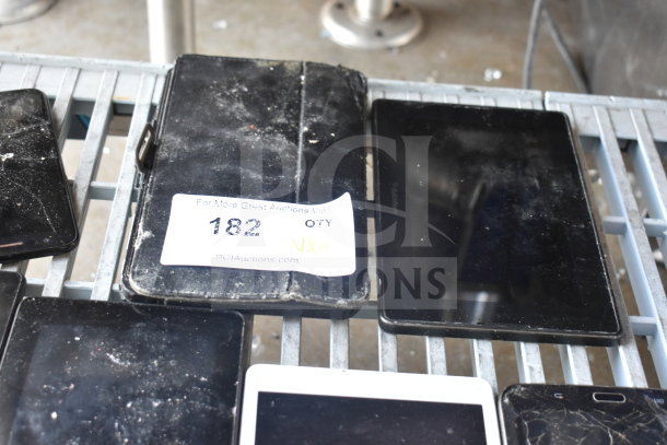 9 assorted tablets with varying conditions, some with visible wear and cracked screens. Auction label marked "182."