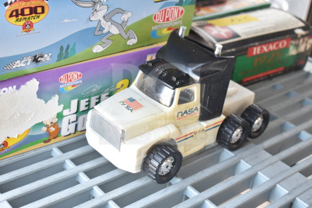 Toy NASA truck with an American flag and "USA" markings, featuring six wheels. Background shows DuPont and Texaco packaging.