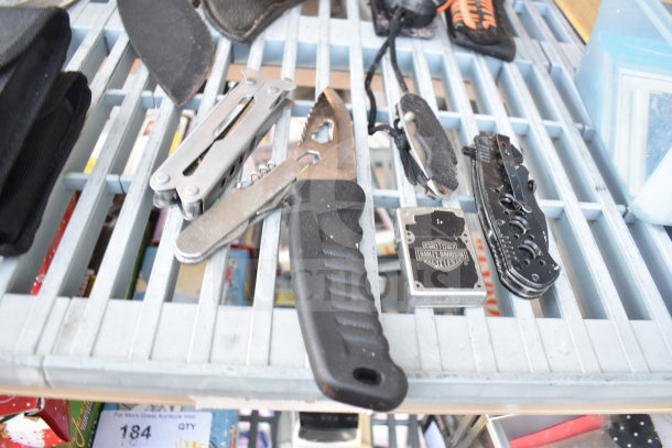 13-piece set including knives, multitools, Harley-Davidson-branded item, and more on a metal rack. Mixed condition.