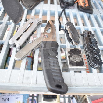 13-piece set including knives, multitools, Harley-Davidson-branded item, and more on a metal rack. Mixed condition.