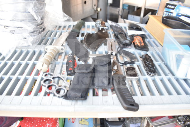 13 assorted items including knives, knuckles, and drill bits on a metal grate. Various conditions, offering mixed utility.