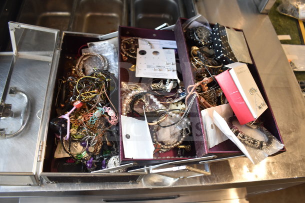 Case of assorted jewelry including necklaces and bracelets, various materials and styles, some in original packaging.