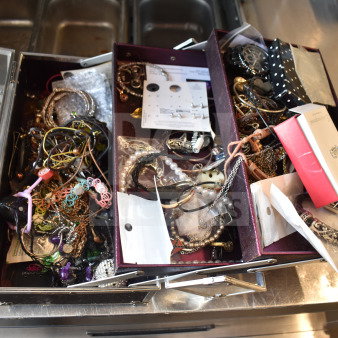 Case of assorted jewelry including necklaces and bracelets, various materials and styles, some in original packaging.