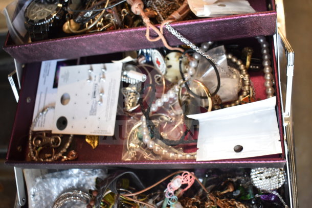 Case of assorted jewelry including necklaces, bracelets, and earrings in mixed materials, some with tags and packaging.