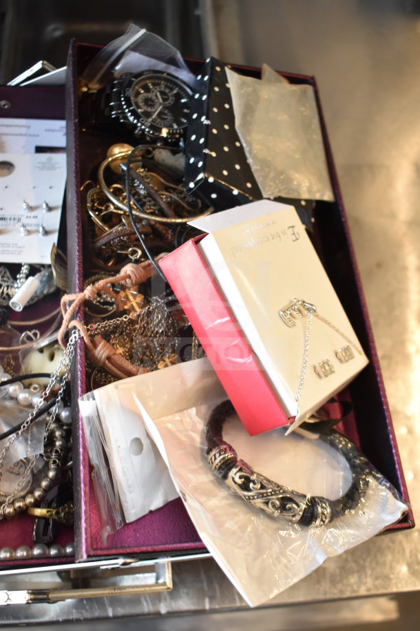 Case of assorted jewelry including various necklaces and bracelets; features metal and bead designs, some in original packaging.