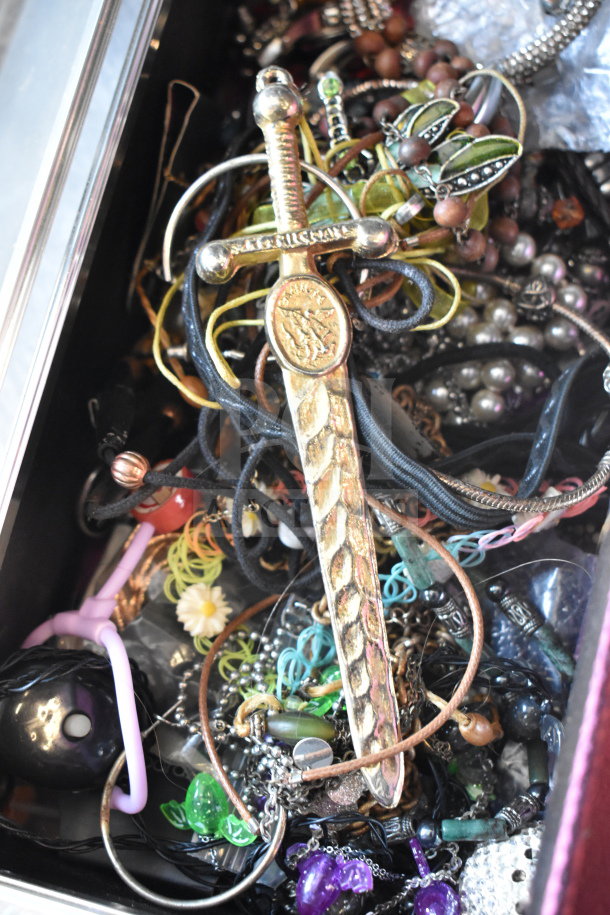 Case filled with assorted jewelry, including various necklaces and bracelets. Features a mix of materials and styles.