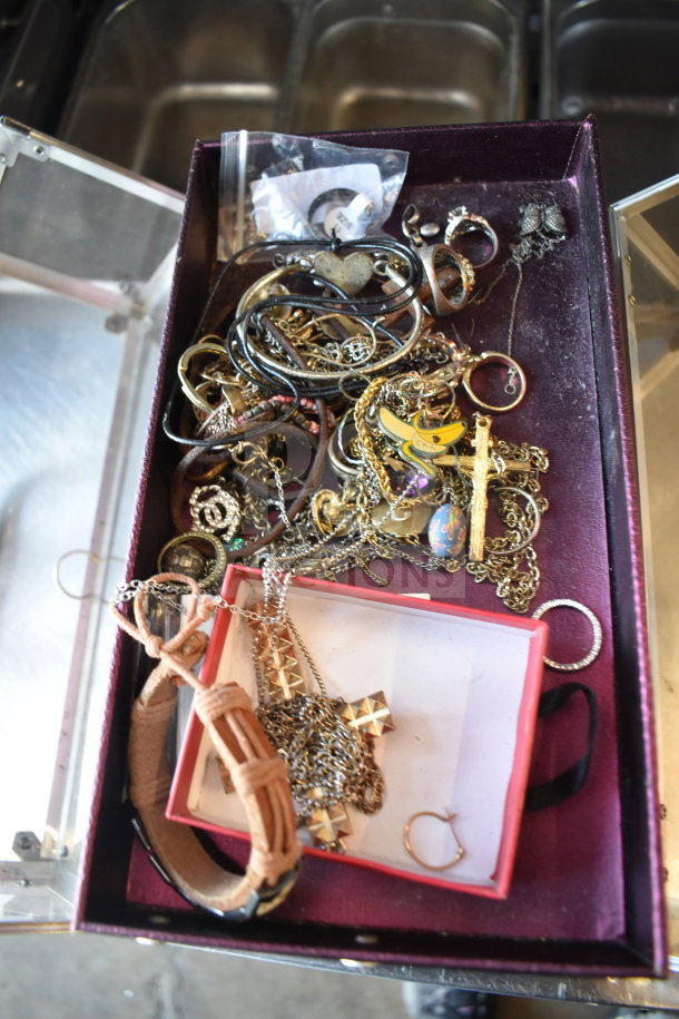 Case of assorted jewelry including varied necklaces and bracelets; features metal chains, pendants, and a leather bracelet.