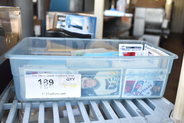 Box of various collectible cards, including ice hockey, in plastic container. Visible auction label and card details.