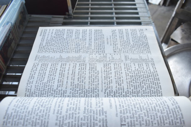 Holy Bible open on a metal rack, showcasing text from the book of Exodus. Pages appear in good condition.