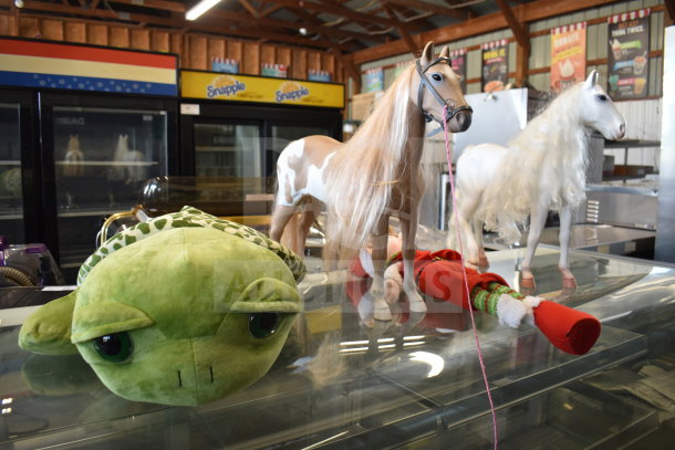 Lot of items includes a green turtle stuffed animal, two play horses with long manes, and a festive elf doll.