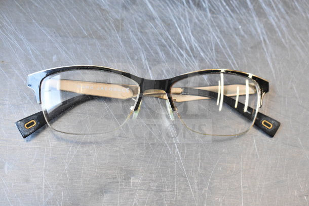 Marc Jacobs black and gold eyeglasses in good condition, featuring a logo on the temples and sturdy frame construction.