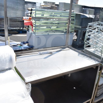 Commercial table with under shelf and casters. Steel construction, used condition. Item tag indicating auction number.