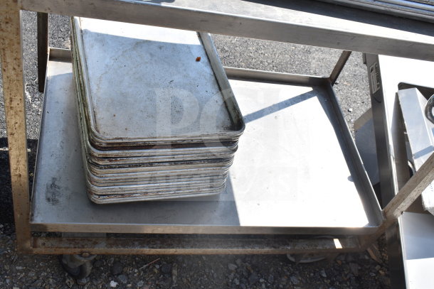 Two-tier metal cart with stacked baking pans, some rust visible on the frame, suitable for catering or bakery use.