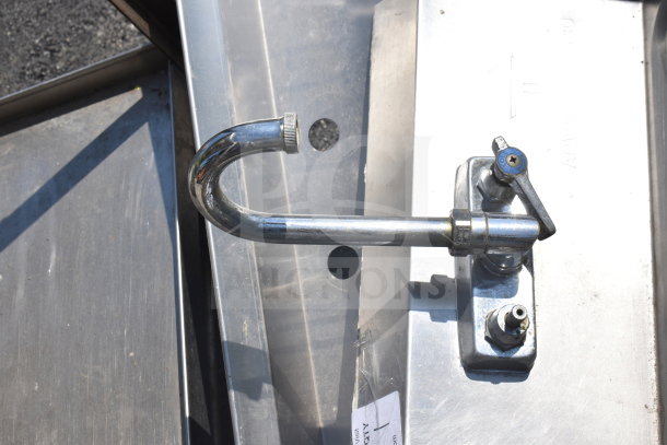 Commercial single bay wall mount sink with faucet and handles, stainless steel, minor wear, suitable for professional use.