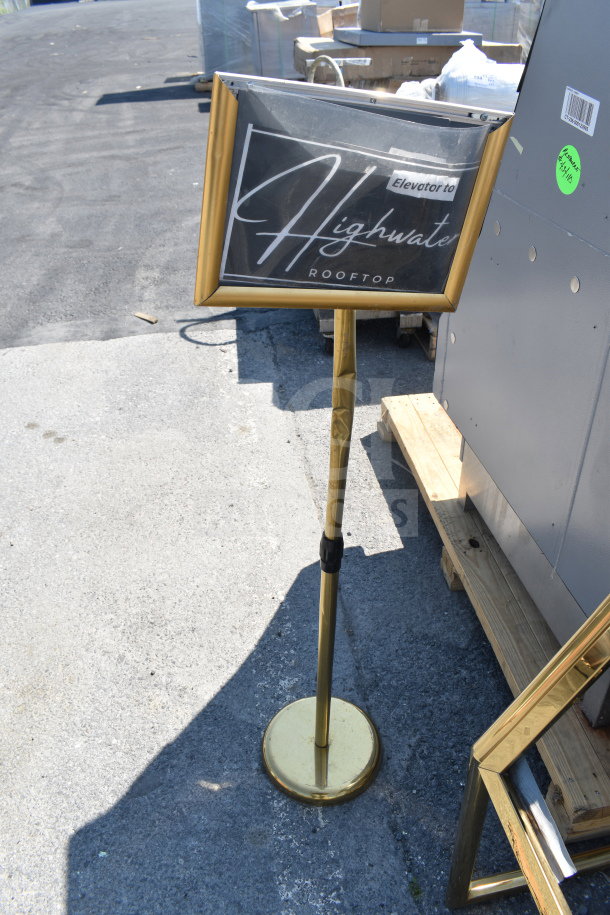 Gold-framed "Elevator to Highwater Rooftop" sign on a stand, used condition, includes additional sign frame.