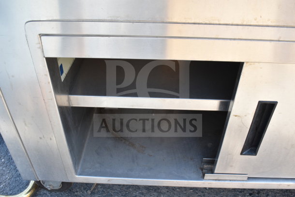 Delfield SC-50-NU 50" serving counter with solid top, enclosed base, stainless steel, visible wear, and wheel casters.