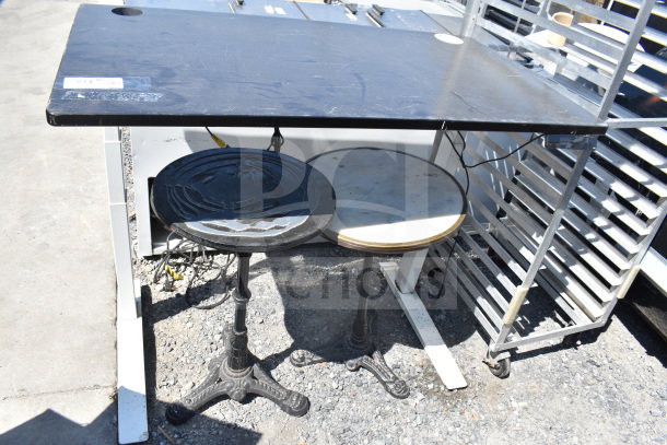 Three various tables: one rectangular black table with slight wear, two round tables, one with ornate metal base and one with marble top.