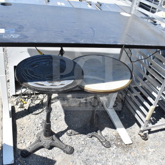 Three various tables: one rectangular black table with slight wear, two round tables, one with ornate metal base and one with marble top.