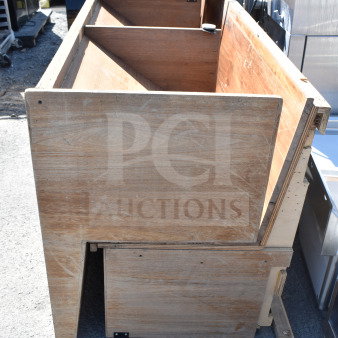 Wooden pattern bench with a simple rectangular design, visible wood grain, and caster wheels. Appears slightly worn.