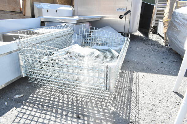 Five chrome finish wire baskets stacked outdoors, part of an auction. Each basket features a durable wire design.