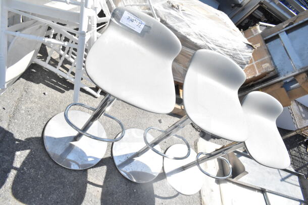 Three brand new low back stools with foot rests, slight scratch and dent condition, white seats, chrome bases.