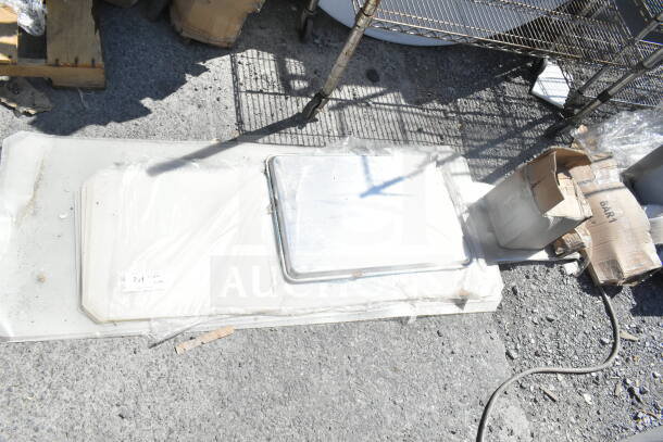 Lot of various items including Tuxton bowls, baking pan, and shelf liners on a concrete surface. Some items in boxes.