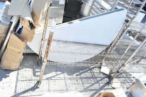 Chrome finish single-tier wire shelving unit on commercial casters. Visible rust on poles. Dismantling required.