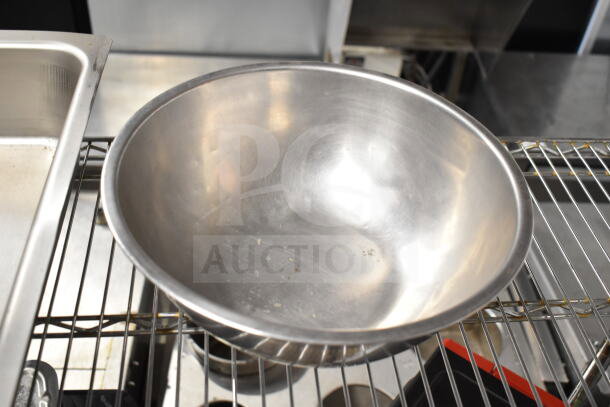 Metal bowl with a shiny surface, slight wear, part of a lot with other kitchen items; visible on a wire rack.