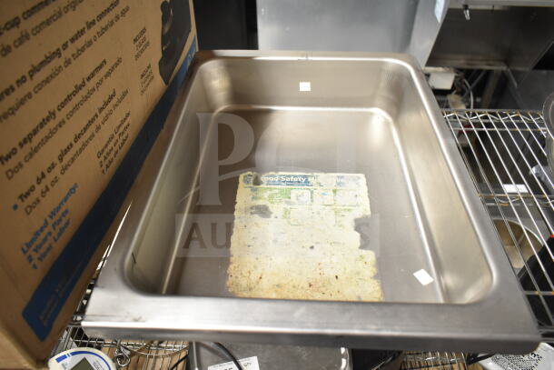 Three metal bowls and a drop-in bin, in used condition. Notable scratches, with a faded safety label inside the bin.
