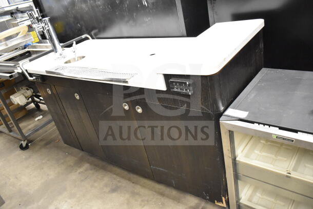 Portable bar with white countertop and dark wood base, featuring a faucet and storage cabinets. Slight wear visible on edges.