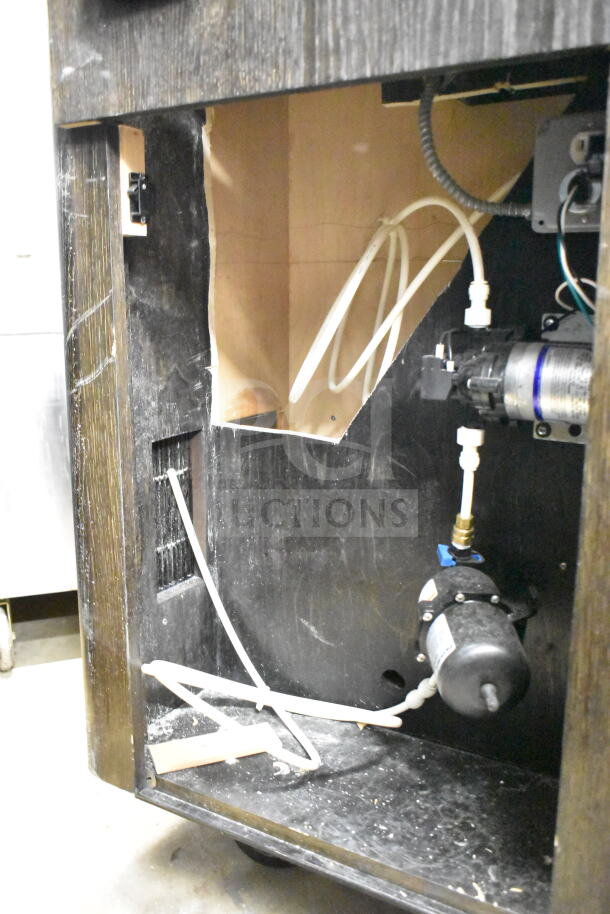 Interior view of a portable bar showing plumbing and wiring components, in used condition with visible scratches.