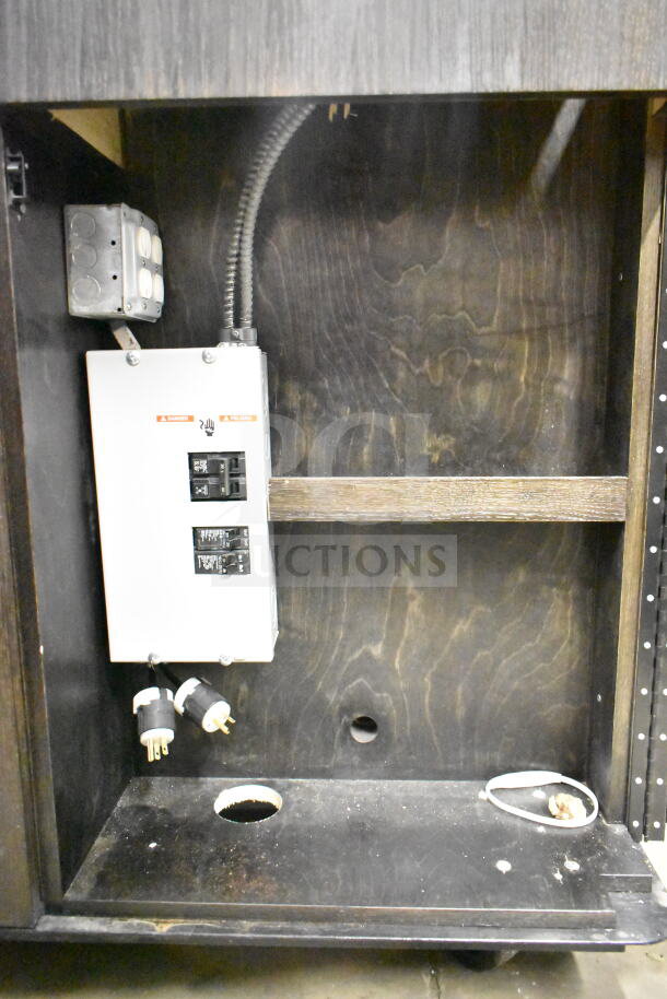 Interior view of a portable bar showing electrical wiring and circuit breakers. Features wood paneling and metal components.