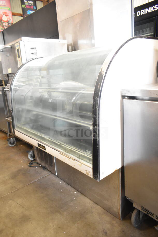 Delfield commercial deli display case, curved glass, floor style, visible wear, mounted on wheels, branded label intact.