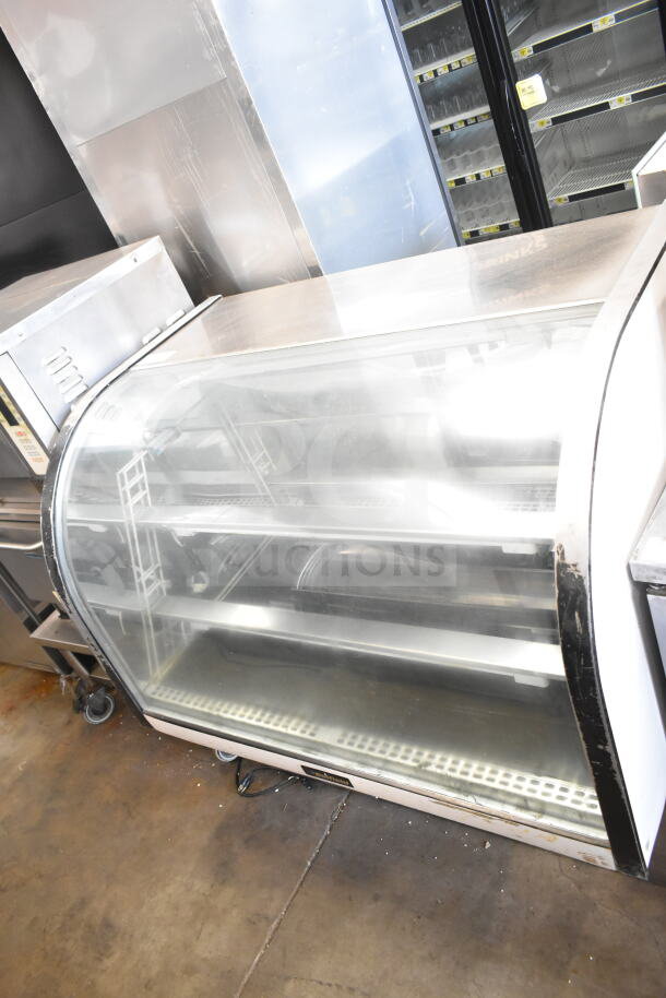 Delfield commercial floor-style deli display case merchandiser, glass-front, three shelves, metal frame, used condition.