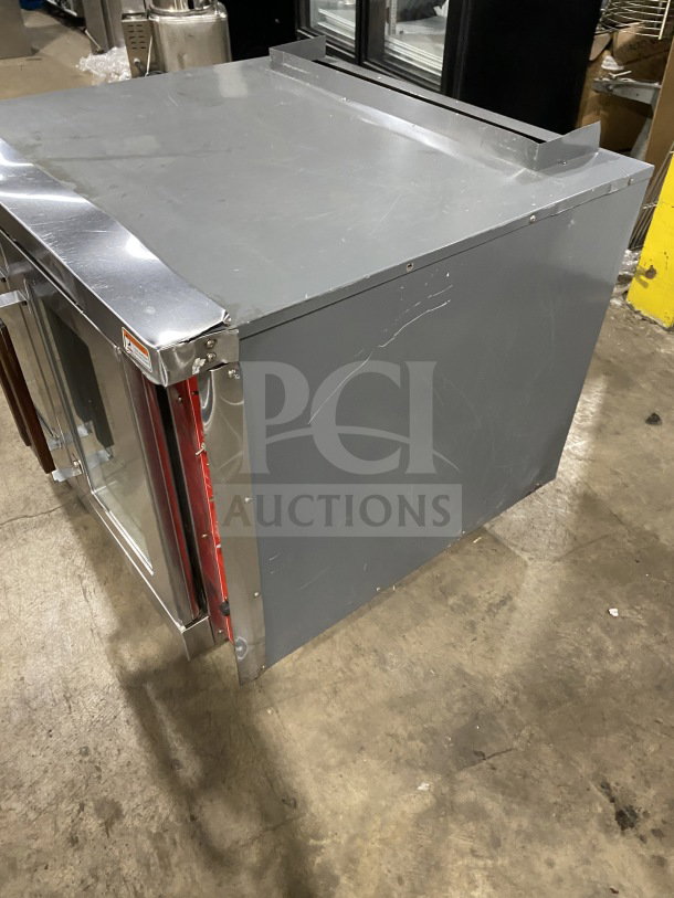 Commercial stainless steel undercounter refrigerator, gray exterior, scratches visible, with glass door and red interior trim.