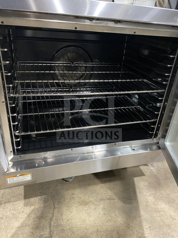 Stainless steel commercial oven with fan and multiple wire racks, in good condition, interior view. Safety instructions label visible.